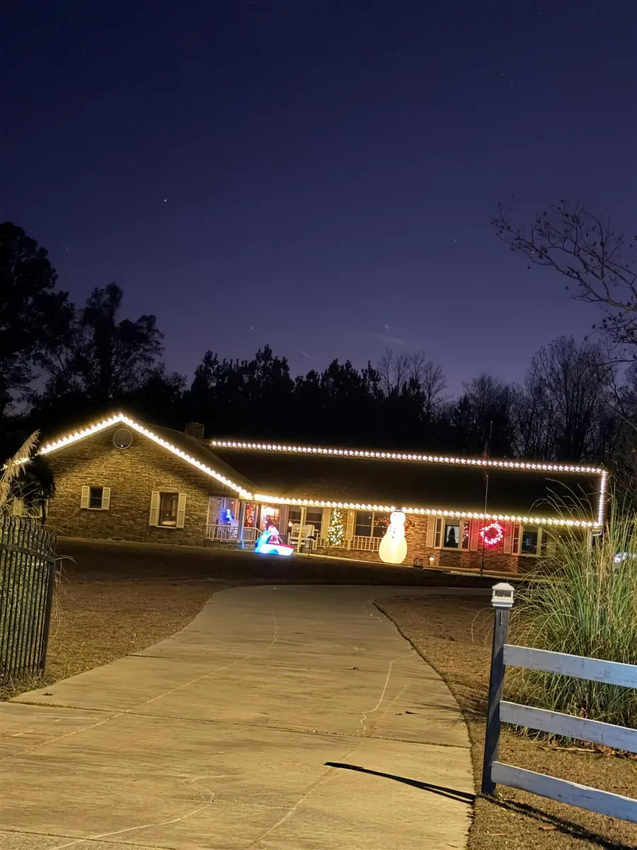 A long brick ranch traced end to end in warm white at blue hour